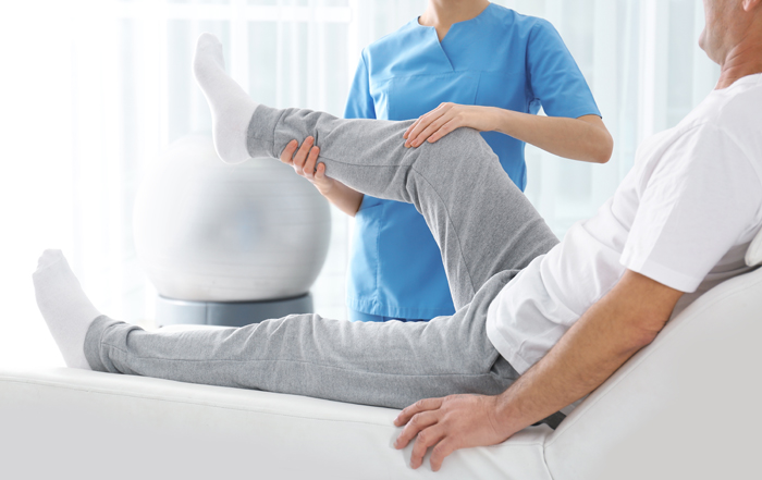 Therapist supporting a patient's bent knee during a leg assessment