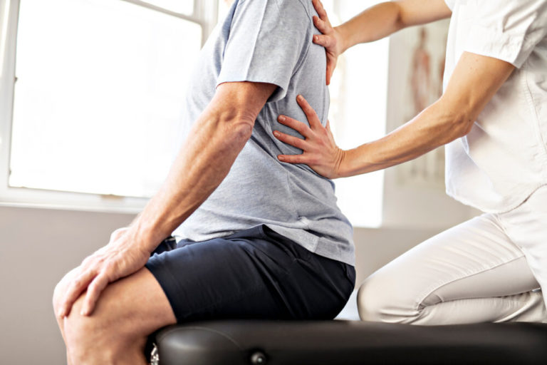Therapist assessing a seated patient's lower back