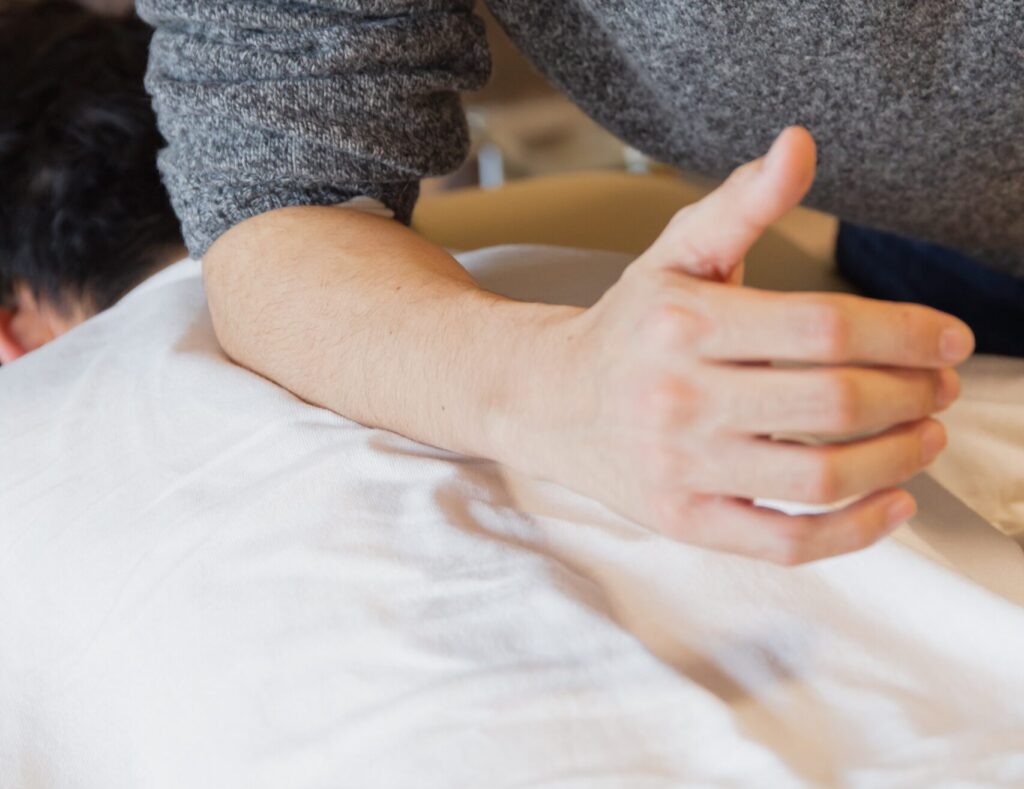 Practitioner applying pressure with a forearm to a patient's back